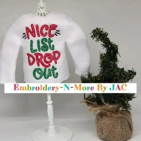 White elf sweater with 'Nice List Drop Out' embroidered in red and green, next to mini Christmas tree.