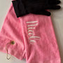 Personalized pink golf towel with embroidered name and black golf glove on white background