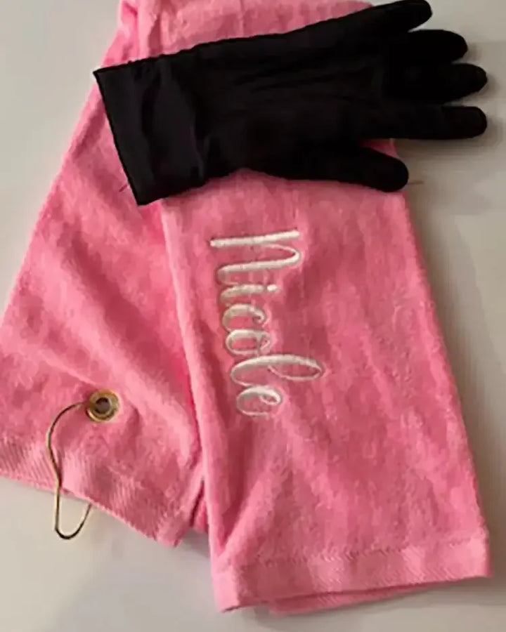 Personalized pink golf towel with embroidered name and black golf glove on white background