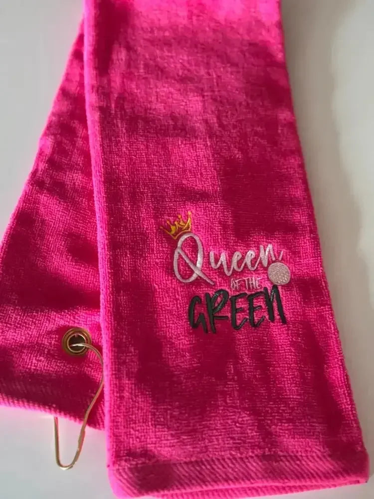 Bright pink embroidered golf towel with 'Queen of the Green' text and a gold grommet
