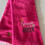 Bright pink embroidered golf towel with 'Queen of the Green' text and a gold grommet