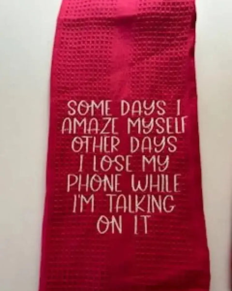 Red kitchen towel with humorous embroidered quote about losing a phone while talking on it