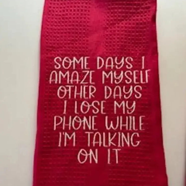 Red kitchen towel with humorous embroidered quote about losing a phone while talking on it