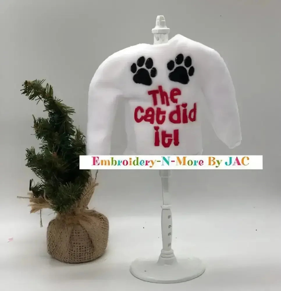White elf sweater with 'The cat did it!' text, black paw prints, and mini Christmas tree.