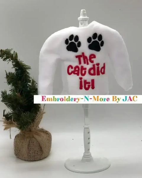 White elf sweater with 'The cat did it!' text, black paw prints, and mini Christmas tree.