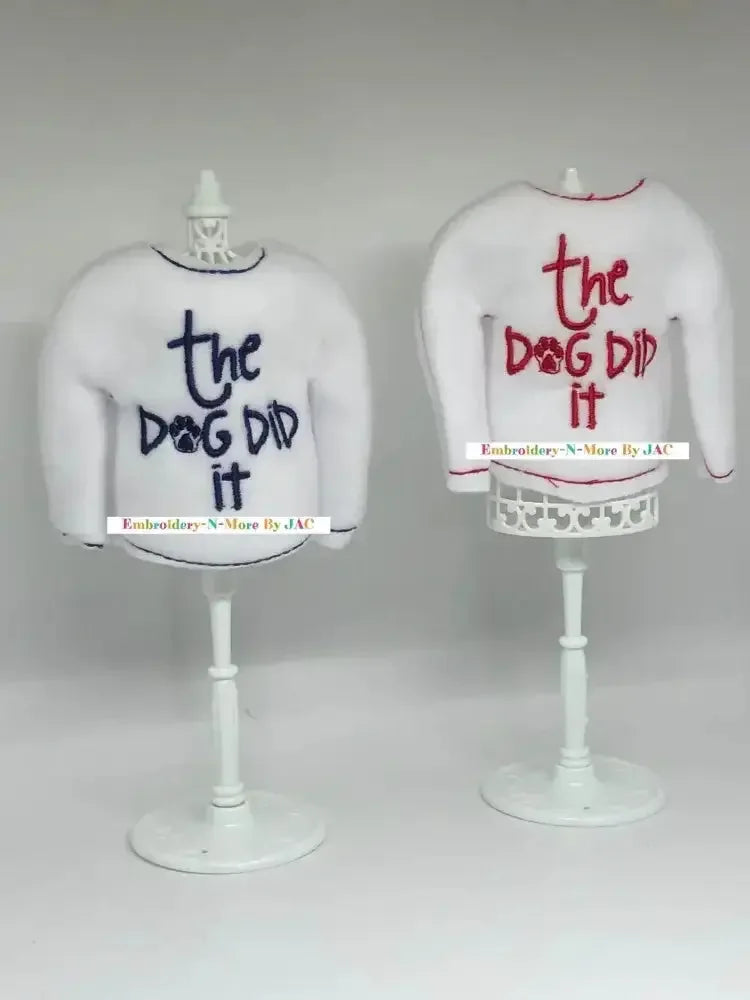 White elf sweaters with 'the dog did it' embroidered in blue and red on stands