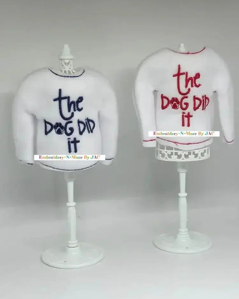 White elf sweaters with 'the dog did it' embroidered in blue and red on stands