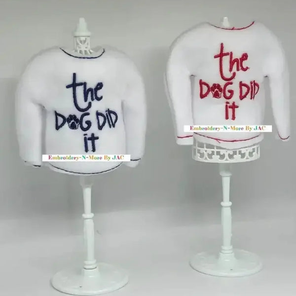 White elf sweaters with 'the dog did it' embroidered in blue and red on stands