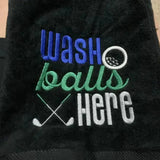 Black embroidered golf towel with 'wash balls here' text, golf ball, and crossed clubs design