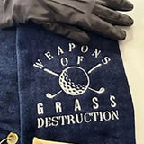Navy embroidered golf towel with 'Weapons of Grass Destruction' design, golf glove, and tees