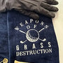 Navy embroidered golf towel with 'Weapons of Grass Destruction' design, golf glove, and tees