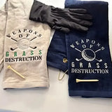Embroidered golf towels with 'Weapons of Grass Destruction' text, golf tees, and glove.