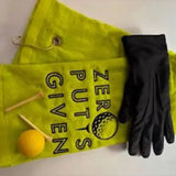 Yellow embroidered golf towel with 'Zero Putts Given' text, golf glove, tees, and ball